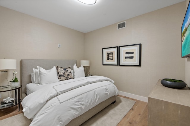 bedroom with visible vents, baseboards, and wood finished floors