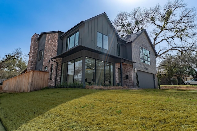 rear view of property featuring a yard, board and batten siding, brick siding, and a garage