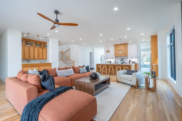 living area featuring a ceiling fan, stairway, light wood-style flooring, and recessed lighting