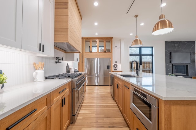 kitchen featuring a sink, light stone counters, stainless steel appliances, light wood finished floors, and custom exhaust hood