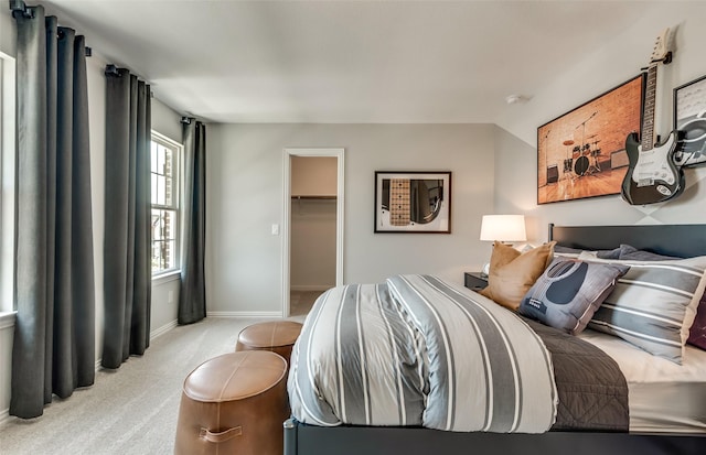 carpeted bedroom with a walk in closet, baseboards, and vaulted ceiling