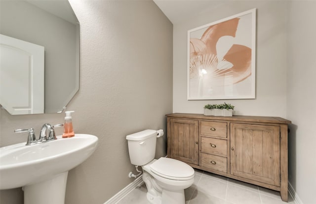 bathroom with tile patterned flooring, toilet, baseboards, and a sink