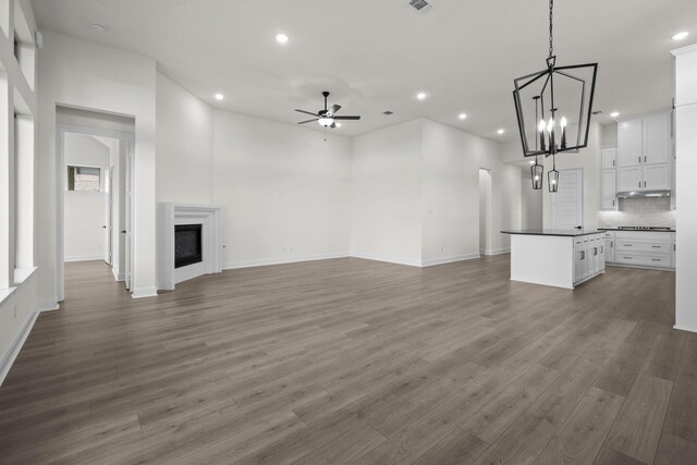 3100 Colt Ln, Celina, TX 75009 - unfurnished living room with recessed lighting, a ceiling fan, wood finished floors, a chandelier, and a glass covered fireplace
