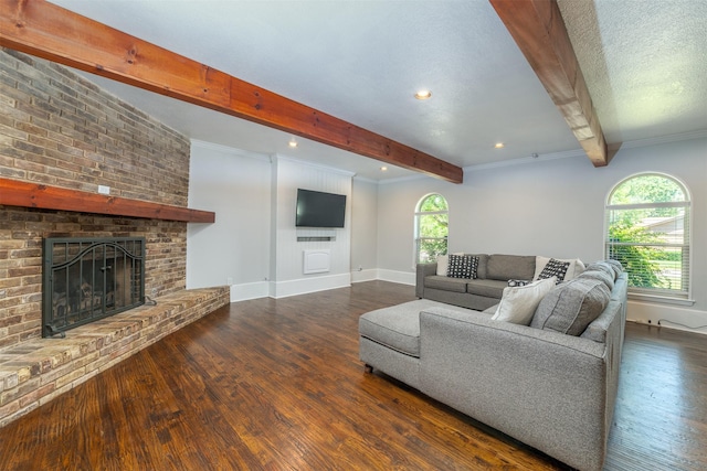 living area featuring beamed ceiling, a textured ceiling, wood finished floors, baseboards, and a brick fireplace