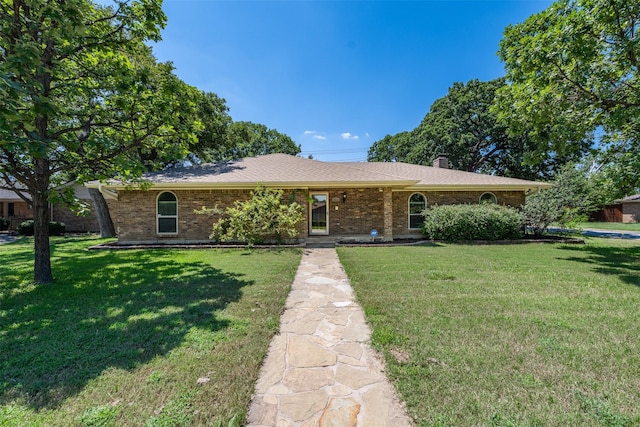 single story home with a front yard, brick siding, and a chimney