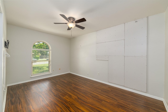 spare room with dark wood-type flooring, baseboards, and ceiling fan