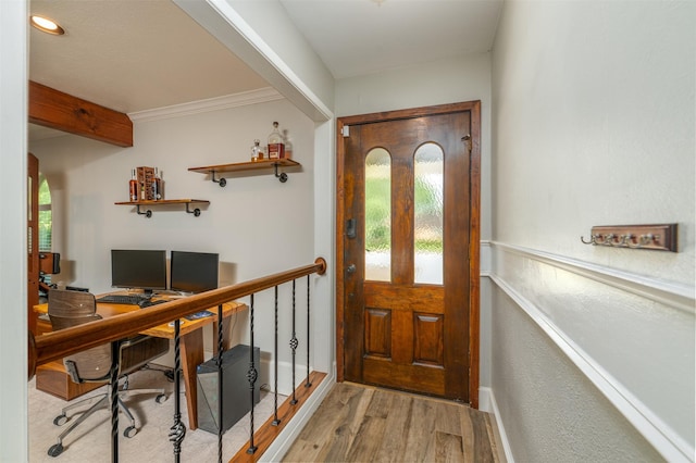 doorway to outside with ornamental molding, wood finished floors, and baseboards