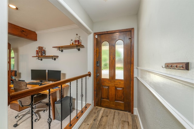 foyer entrance with a wealth of natural light, crown molding, and wood finished floors