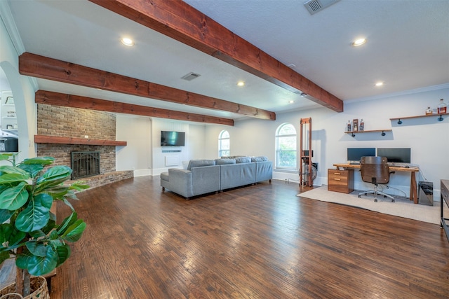 living room with beam ceiling, a brick fireplace, wood finished floors, and visible vents