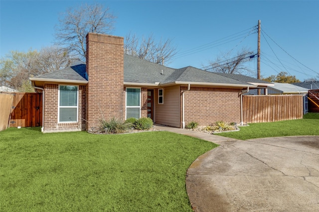 view of front of house with brick siding, a chimney, a front yard, and fence