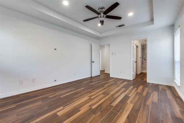 unfurnished bedroom with visible vents, baseboards, recessed lighting, dark wood-style floors, and a raised ceiling