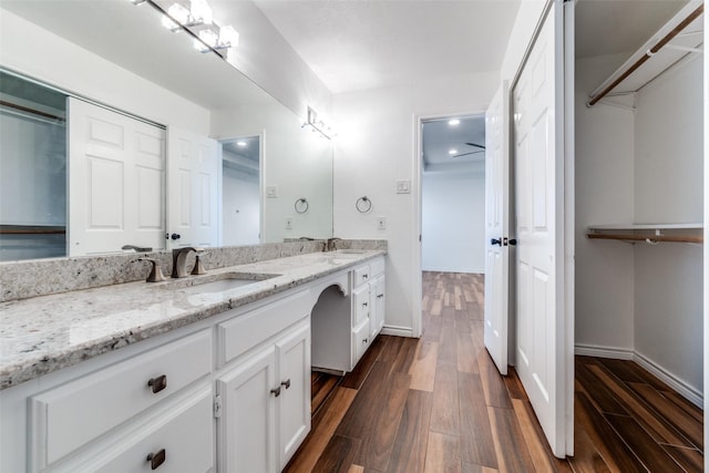 full bath featuring double vanity, wood finished floors, and a sink