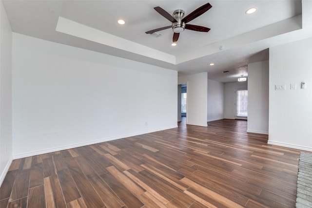 spare room with a tray ceiling, recessed lighting, wood finished floors, and baseboards