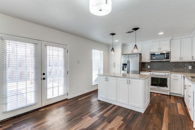 kitchen featuring visible vents, tasteful backsplash, a kitchen island, appliances with stainless steel finishes, and dark wood-style flooring