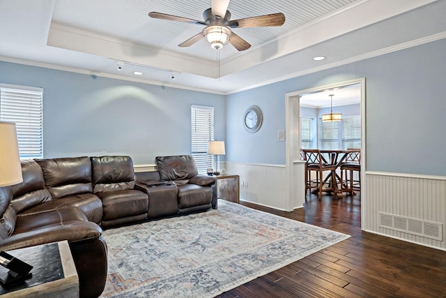 living room featuring visible vents, a raised ceiling, and wainscoting