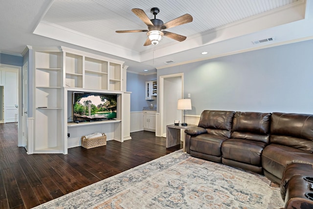 living room featuring visible vents, dark wood-type flooring, ornamental molding, a tray ceiling, and ceiling fan