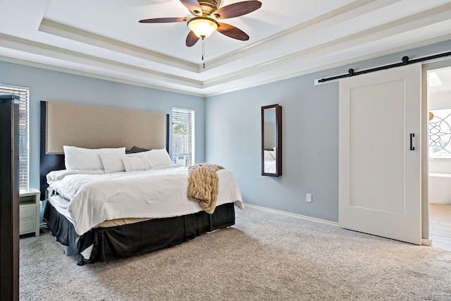 bedroom with baseboards, a tray ceiling, a barn door, and carpet floors