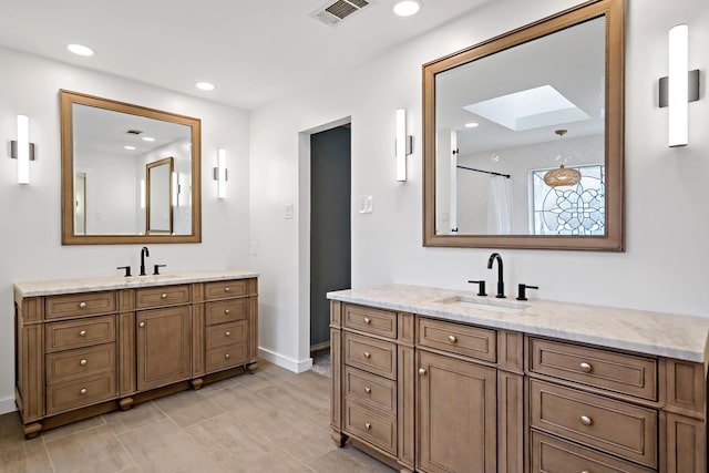 bathroom featuring visible vents, recessed lighting, two vanities, and a sink