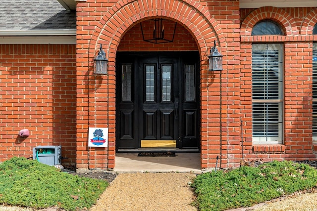 entrance to property with brick siding and roof with shingles