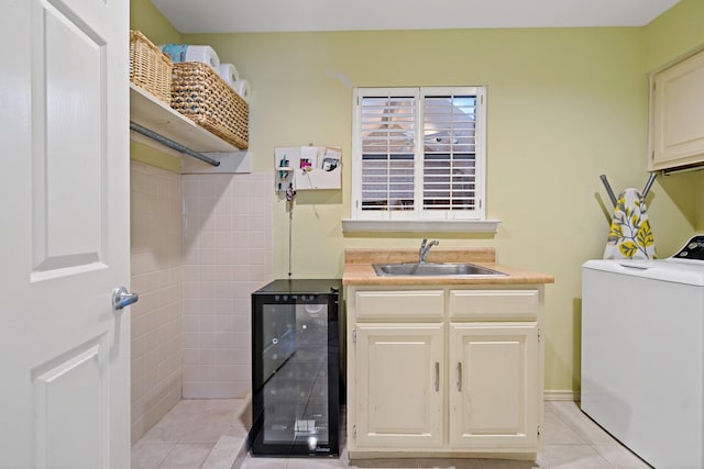 laundry area featuring wine cooler, light tile patterned flooring, cabinet space, washer / clothes dryer, and a sink