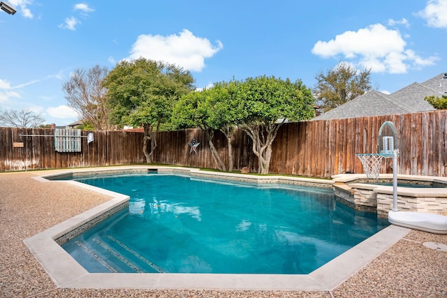 view of swimming pool with a fenced backyard and a pool with connected hot tub