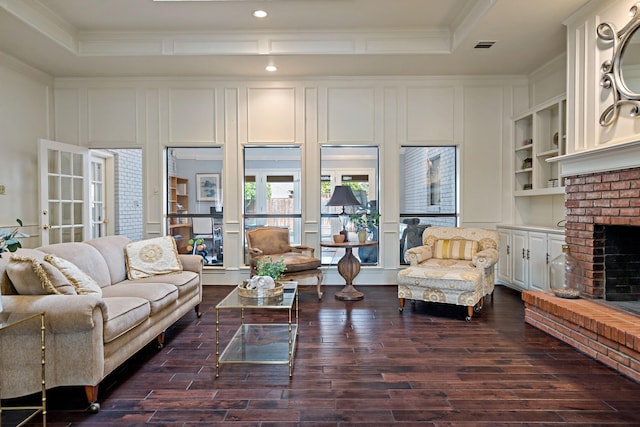 living area with a fireplace, a raised ceiling, and ornamental molding