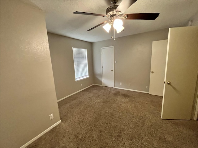 carpeted spare room featuring baseboards, a textured ceiling, and ceiling fan