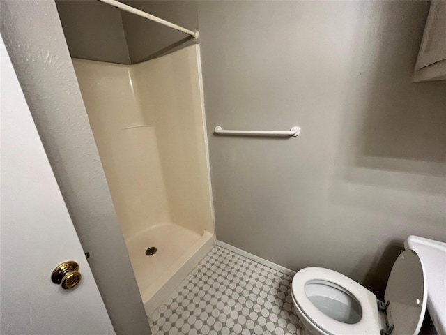 full bathroom featuring tile patterned floors, a stall shower, toilet, and baseboards