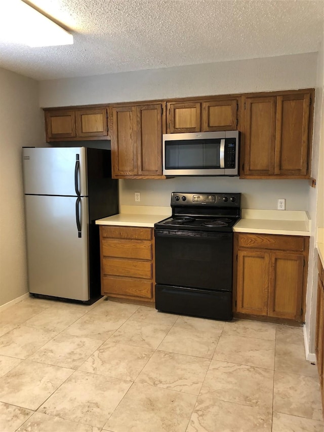 kitchen featuring brown cabinets, appliances with stainless steel finishes, and light countertops