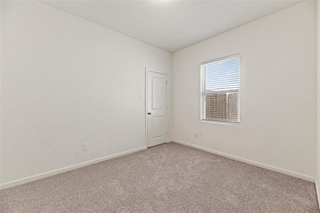 empty room featuring light colored carpet and baseboards