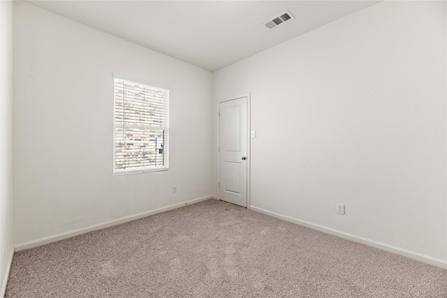 empty room featuring visible vents, light colored carpet, and baseboards