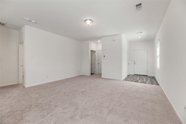 spare room with recessed lighting, carpet, visible vents, and baseboards