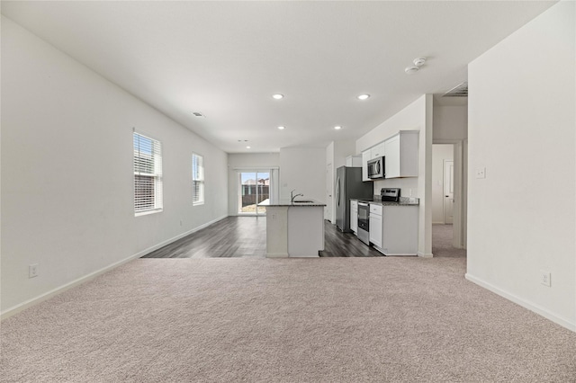 kitchen with an island with sink, open floor plan, dark carpet, recessed lighting, and appliances with stainless steel finishes