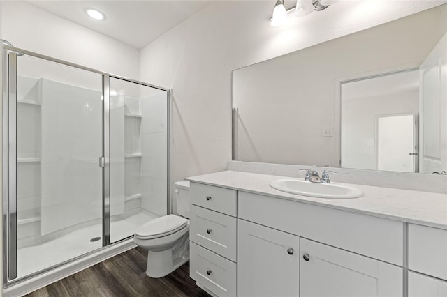 full bath with toilet, a stall shower, wood finished floors, recessed lighting, and vanity