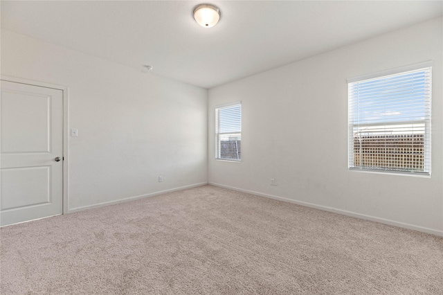 carpeted empty room featuring baseboards