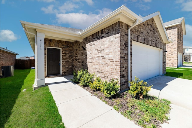 view of exterior entry featuring brick siding, a lawn, cooling unit, and a garage