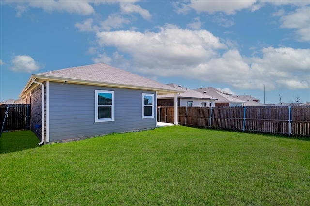 back of house featuring a yard, a fenced backyard, and a shingled roof