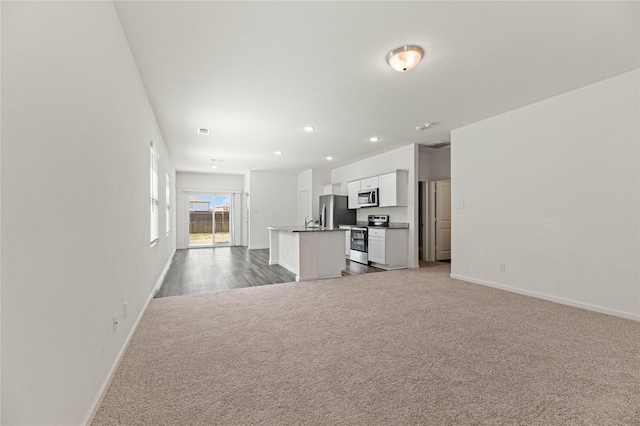 unfurnished living room with recessed lighting, baseboards, carpet floors, and a sink