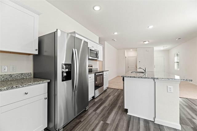 kitchen with light stone counters, dark wood finished floors, appliances with stainless steel finishes, and a kitchen island with sink