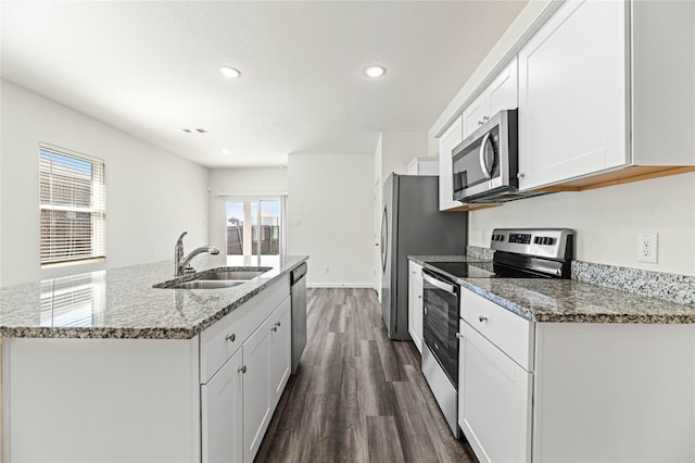 kitchen with an island with sink, a sink, dark wood finished floors, white cabinetry, and stainless steel appliances