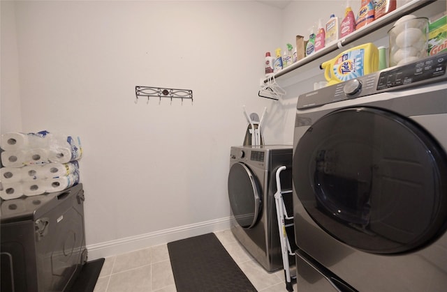 laundry area with laundry area, light tile patterned floors, washing machine and dryer, and baseboards