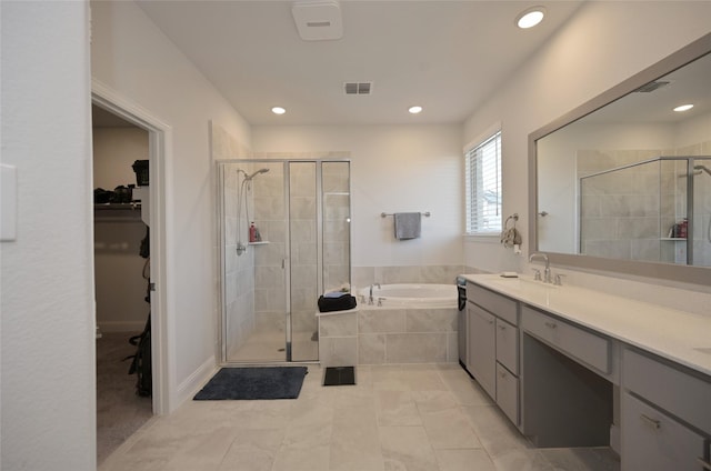 full bath featuring visible vents, a shower stall, a walk in closet, a garden tub, and vanity