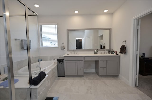 full bathroom featuring double vanity, a stall shower, a garden tub, and a sink