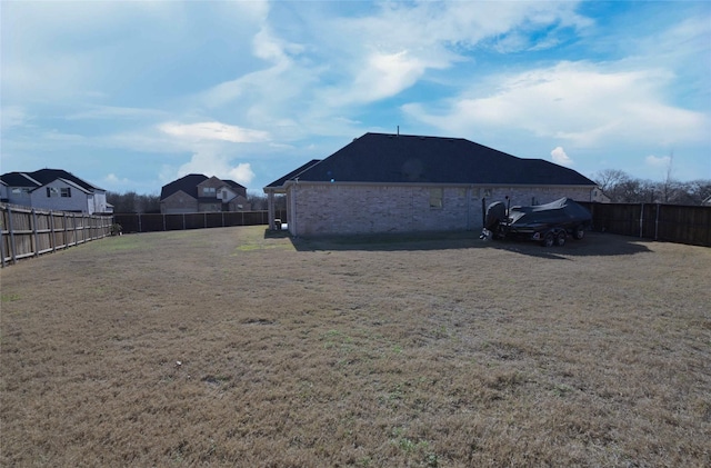 view of side of property featuring brick siding, a lawn, and a fenced backyard