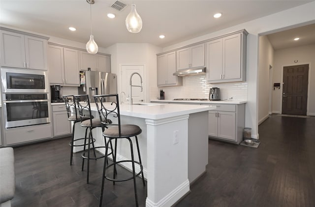 kitchen featuring visible vents, under cabinet range hood, gray cabinets, stainless steel appliances, and a sink