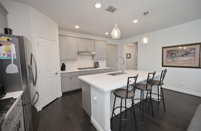 kitchen featuring visible vents, a sink, gray cabinetry, stainless steel appliances, and under cabinet range hood