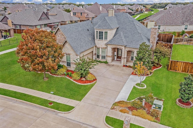 french country inspired facade featuring fence, a residential view, a chimney, stone siding, and driveway