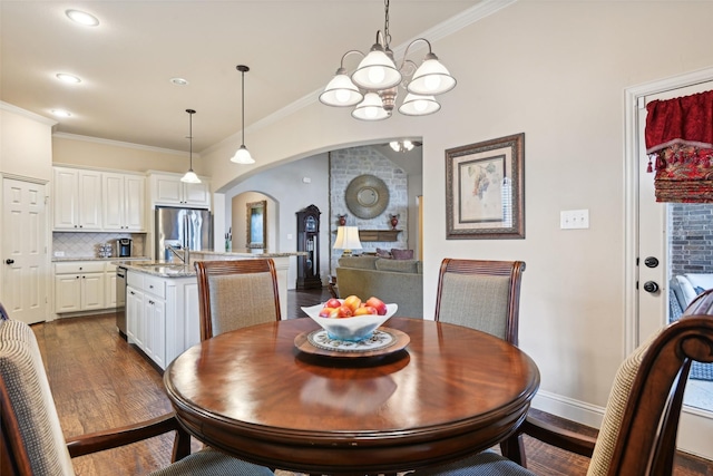 dining space with crown molding, baseboards, dark wood-type flooring, an inviting chandelier, and arched walkways