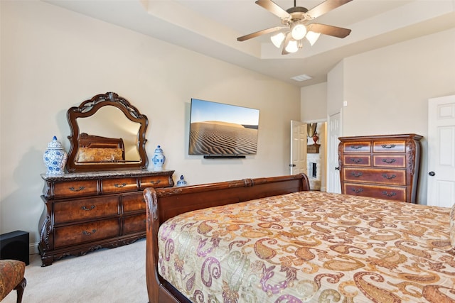 carpeted bedroom with a tray ceiling, visible vents, and a ceiling fan