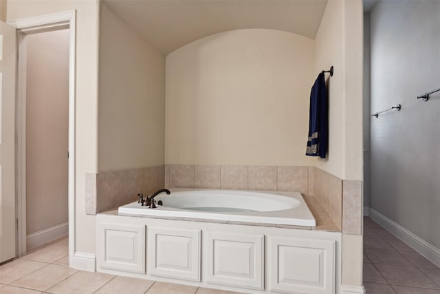 bathroom featuring baseboards, a bath, vaulted ceiling, and tile patterned flooring